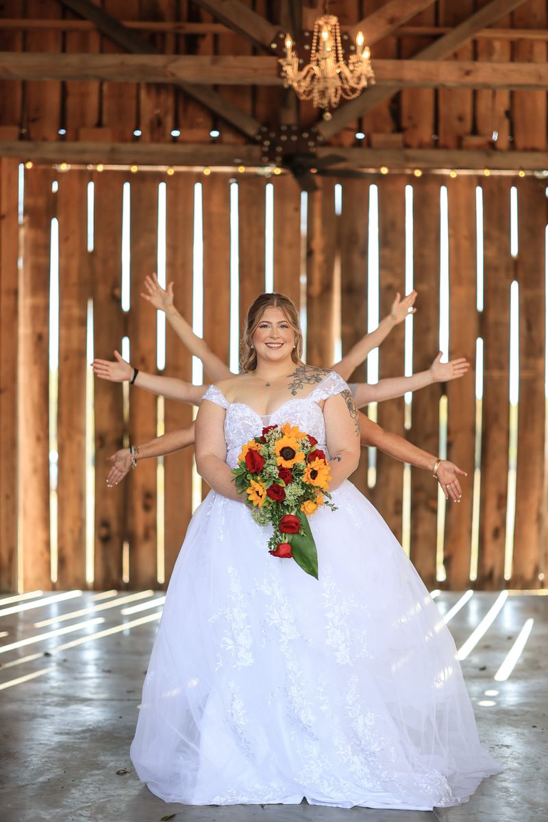 Rebecca holding her sunflower bouquet in the barn